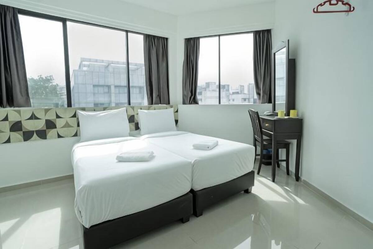A hotel room with a large bed, a desk, and a view of the city.