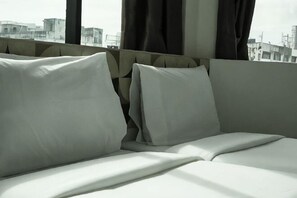 A bed with white linens and a city view through the window. - Grand Bagan Hotel (Butterworth)