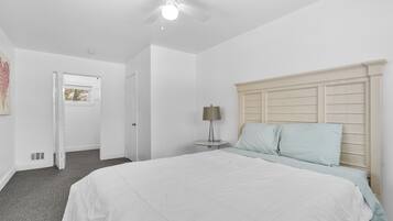 A bedroom with a large bed, a ceiling fan, and a bedside table with a lamp.