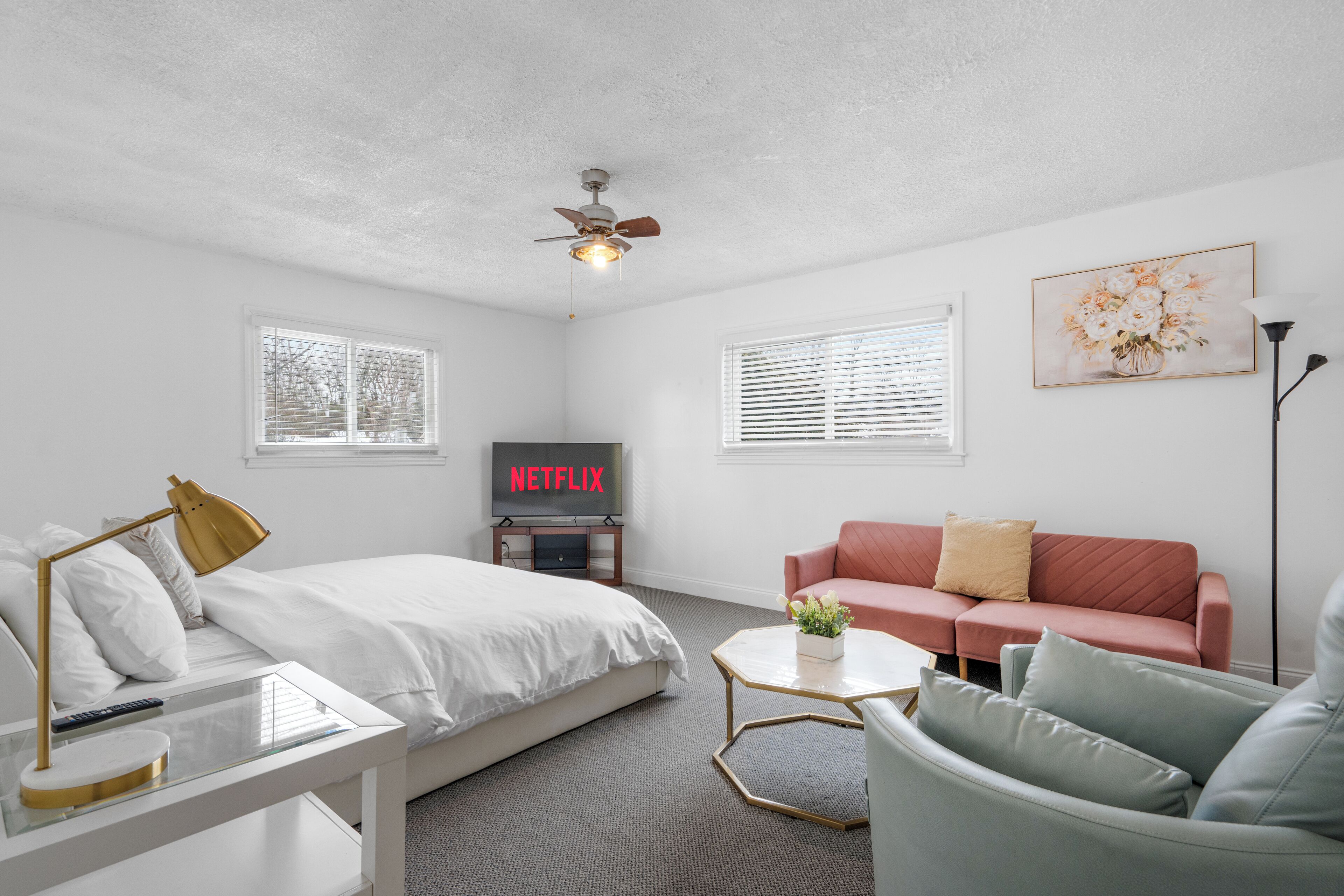 Habitació d'hotel moderna amb llit, sofà, taula de cafè i televisió que mostra 'NETFLIX'.