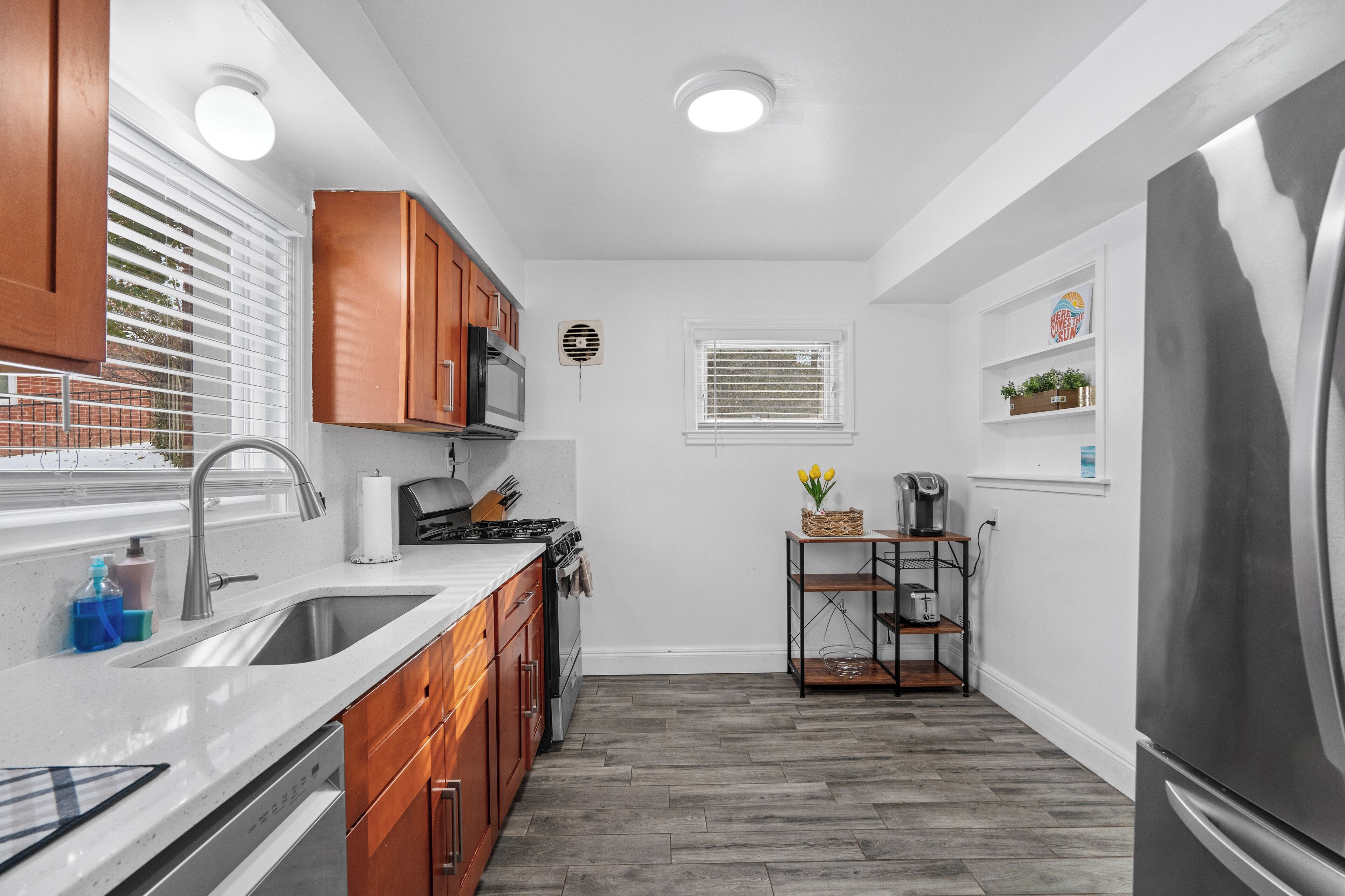 A compact kitchen with wooden cabinets, a stainless steel refrigerator, and a built-in oven.