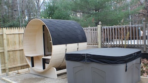Une maisonnette en bois avec un toit noir et un parc pour enfants gris attenant.