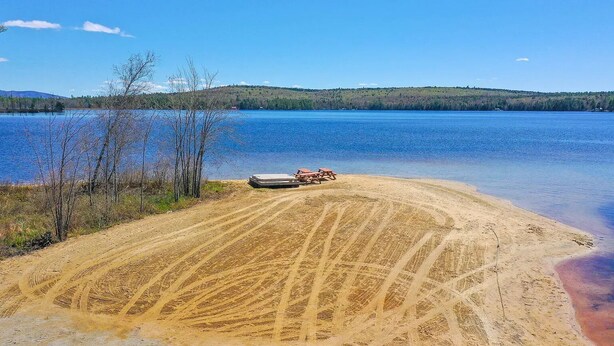 Une plage de sable où l’on voit des traces de pneus menant à un quai.