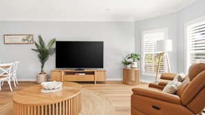 Uma sala de estar moderna com televisão de tela plana, mobiliário de madeira e plantas em vasos.