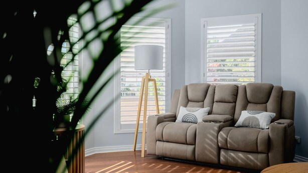 A living room with a beige sofa, a floor lamp, and a large window with blinds. - The Jetty Retreat - 1km from Jetty Beach (Coffs Harbour)