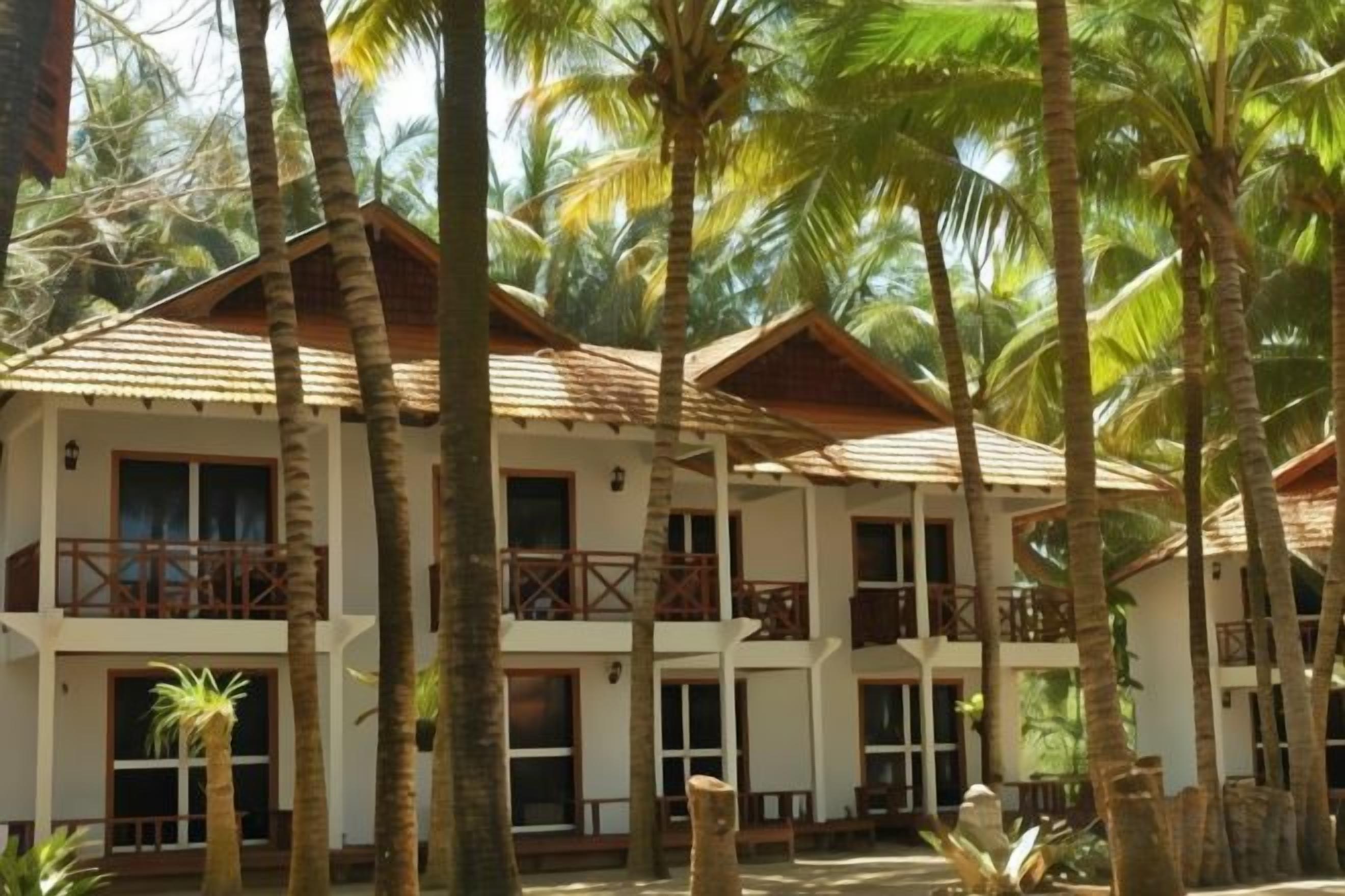 A multi-story hotel with balconies, surrounded by palm trees.