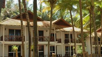 A multi-story hotel with balconies, surrounded by palm trees.