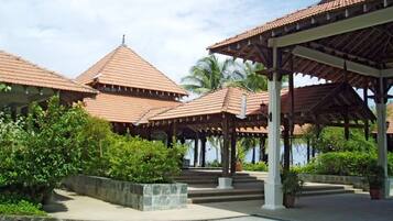 A traditional building with multiple roofed structures, a paved walkway, and greenery.