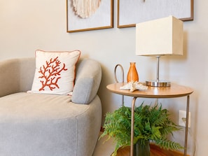 A living room with a grey sofa, a white lamp on a small table, and a potted plant. - Casa Refugio Vista Mar - Nautilus Penha (Penha)