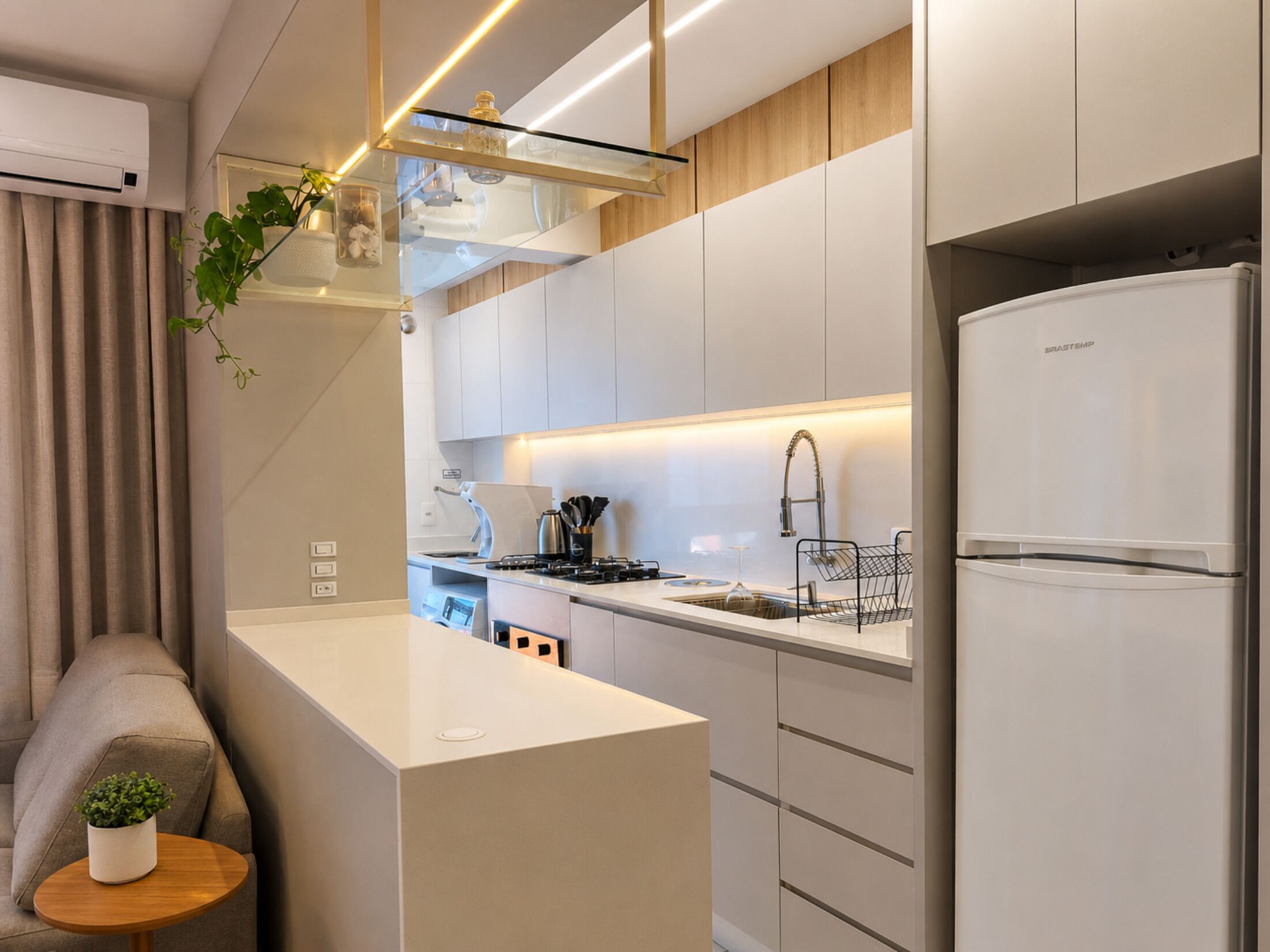 Une cuisine moderne avec des meubles blancs, un four encastré et un réfrigérateur en acier inoxydable.