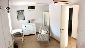 A bedroom with a bed, a desk, a chair, a dresser, a mirror, and a red rug.