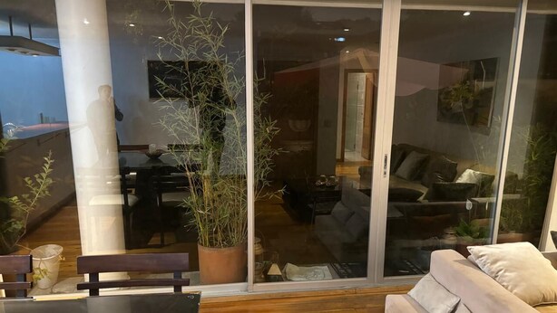 En moderne stue med en glasdør, der fører til en balkon, trægulv, sofa og spisebord.