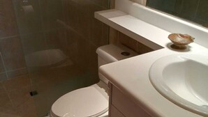 Et badeværelse med toilet, håndvask og bruseområde.