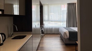 Une chambre d’hôtel moderne dotée d’une kitchenette, d’un lit et offrant une vue sur la ville.