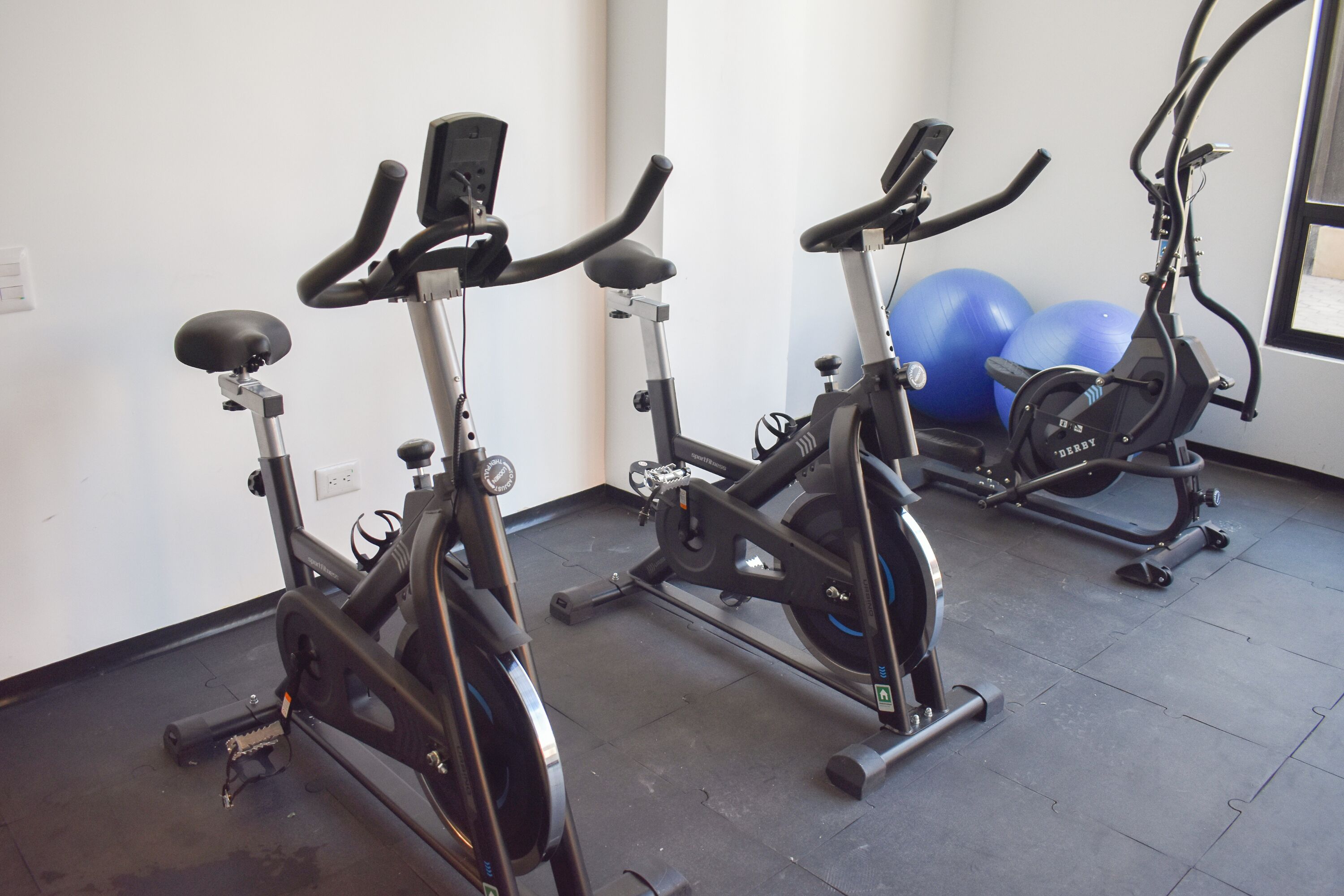 Un gimnasio con bicicletas estáticas y pelotas de ejercicio.