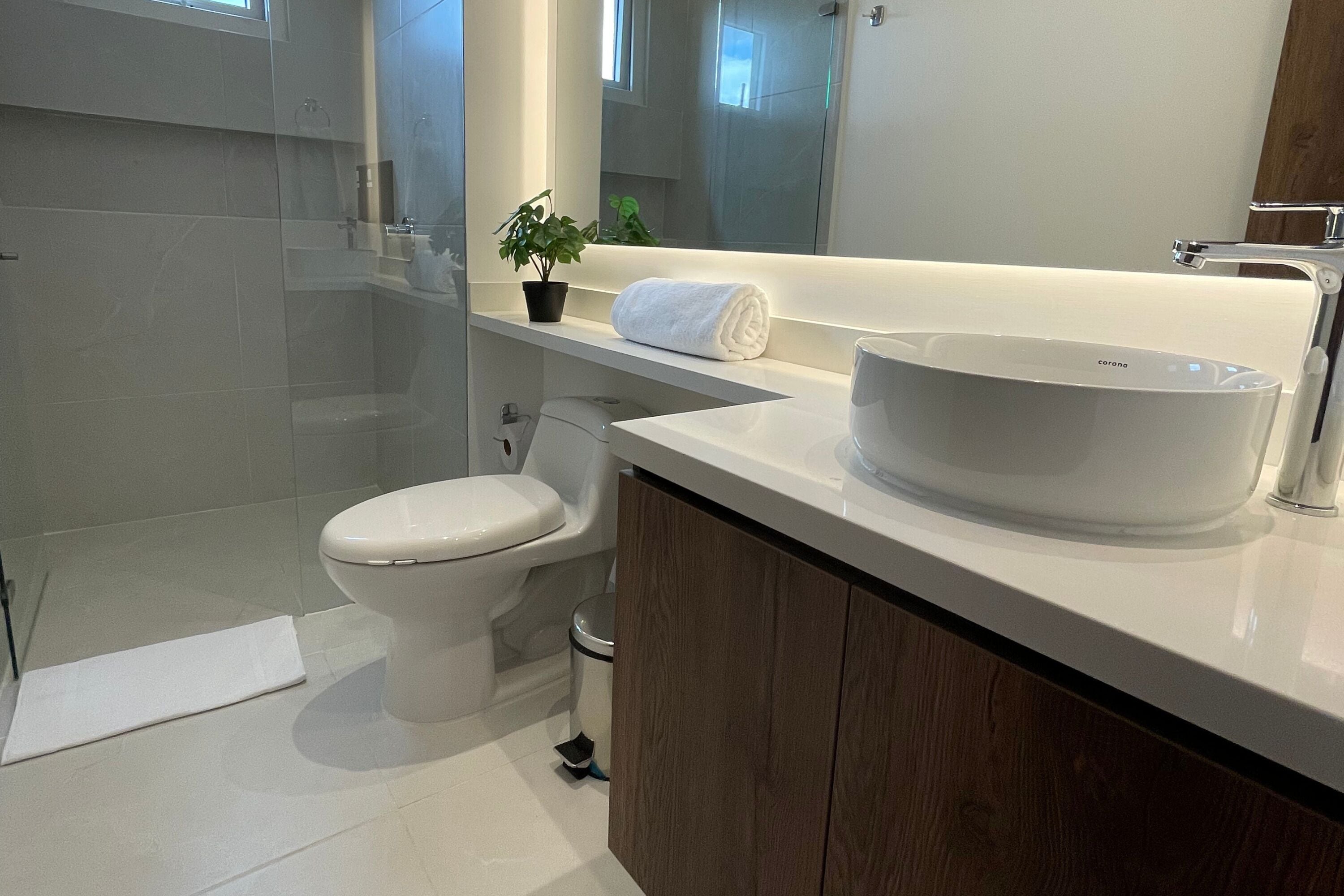 Une salle de bain moderne avec un lavabo, des toilettes et une douche, le tout de couleur blanche.