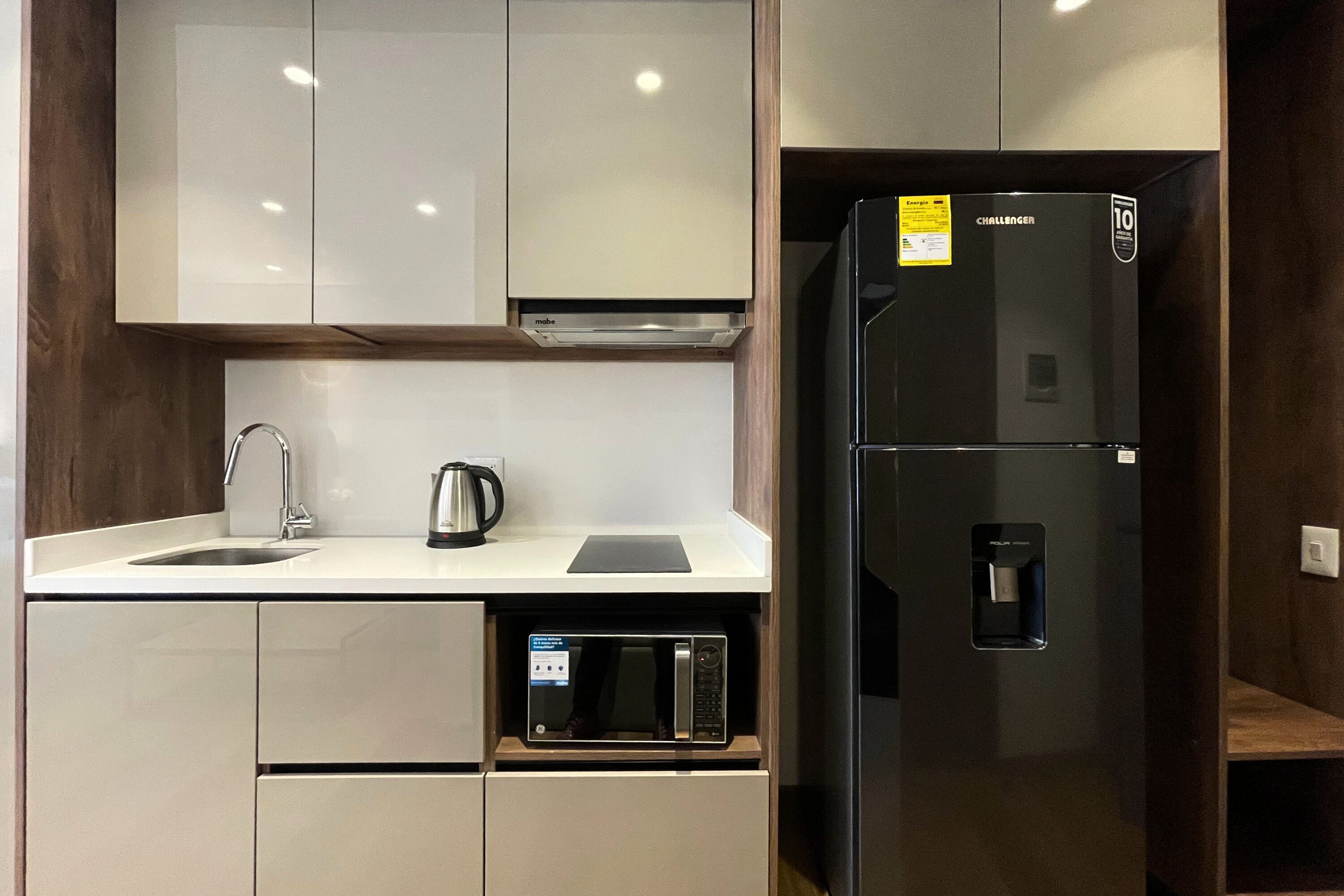 A compact kitchen with a built-in microwave, a refrigerator, and a sink.