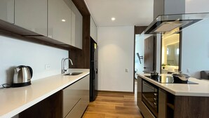 Une cuisine moderne avec des meubles en bois, une bouilloire en acier inoxydable et un four encastré.