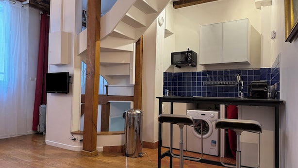 Cocina compacta con microondas, lavadora y una pequeña mesa.