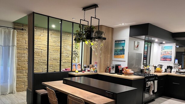 Una cocina moderna con una isla central, muebles negros y una pared decorativa de piedra.