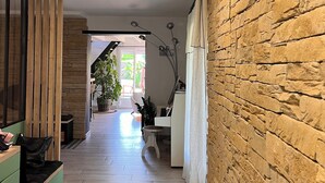 Un pasillo con pared de piedra, suelo de madera y una pared verde a un lado.