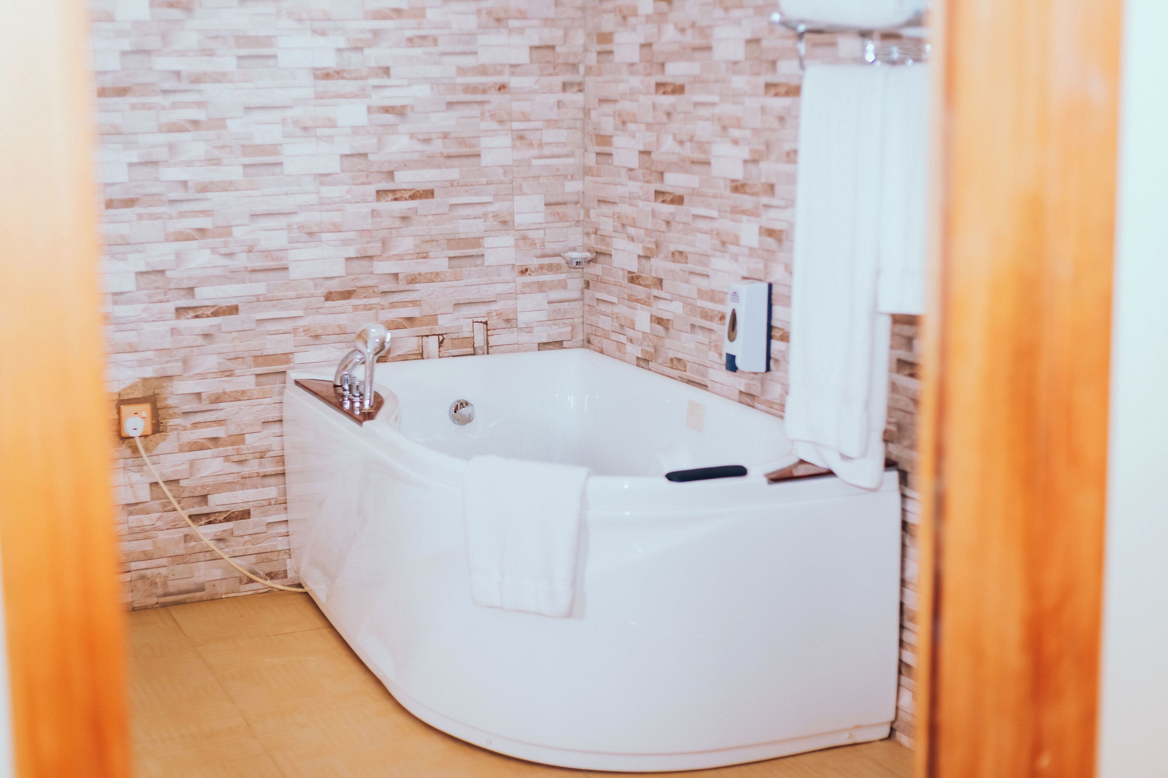 A bathroom with a white bathtub, a white towel, and a shower area.