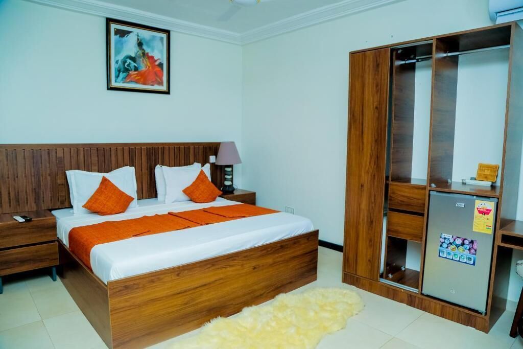 A bedroom with a wooden bed, a nightstand, a wardrobe, and a painting on the wall.