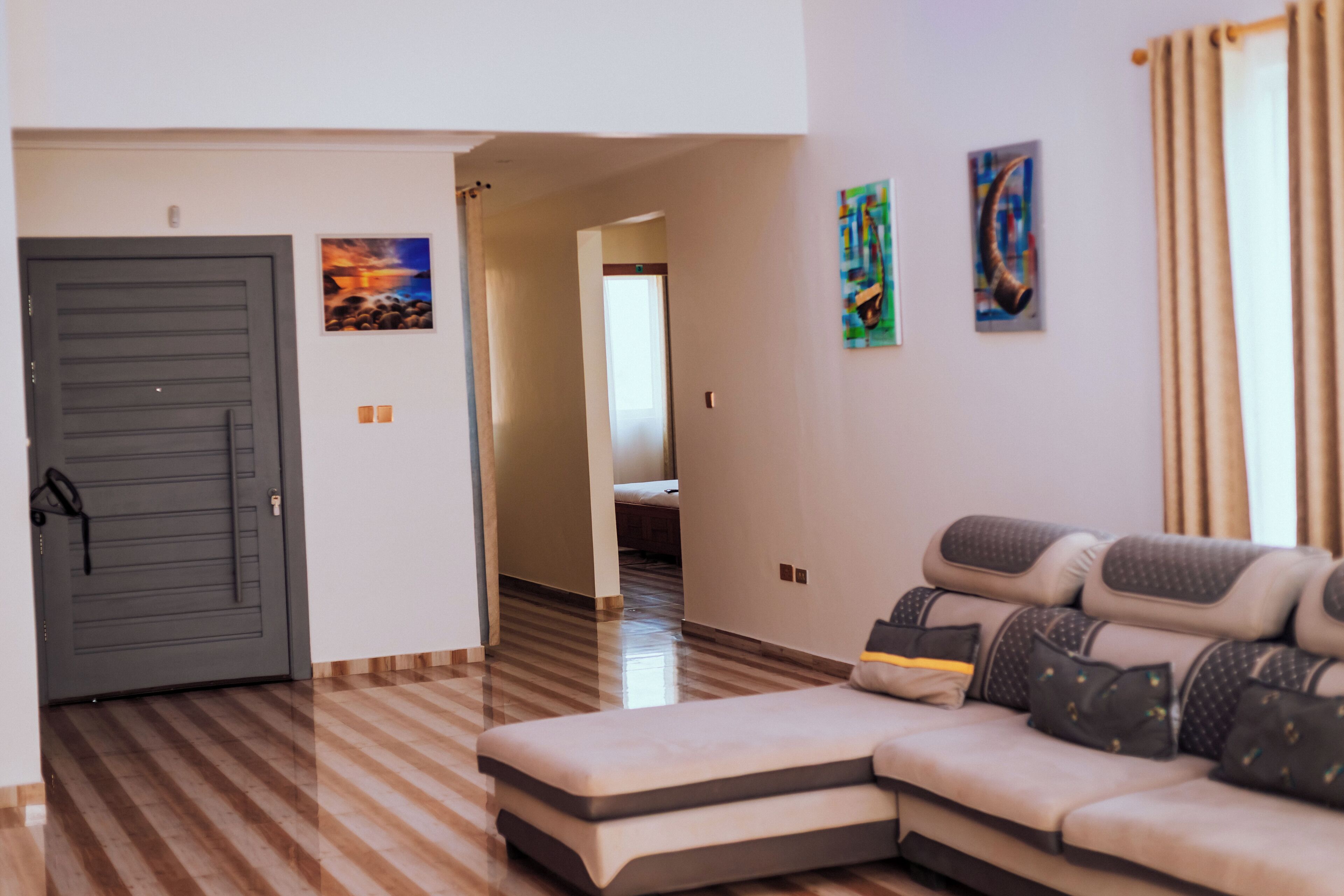 A modern living room with a sofa, a door, and a hallway leading to another room.