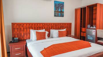 A hotel room with a wooden headboard, white bedding, and an orange throw blanket.