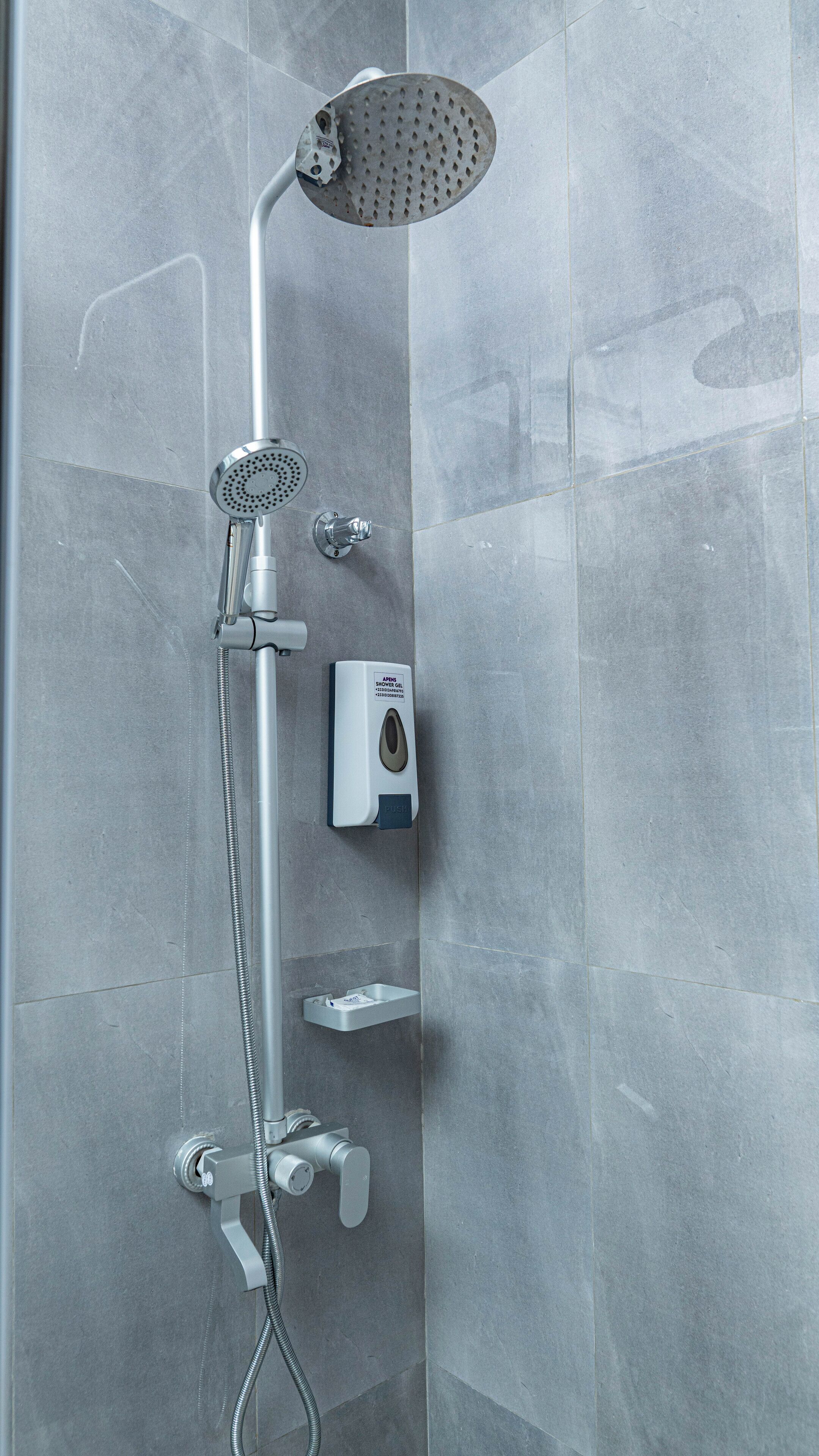 A modern shower with a handheld showerhead, a wall-mounted rain showerhead, and a handheld shower hose.