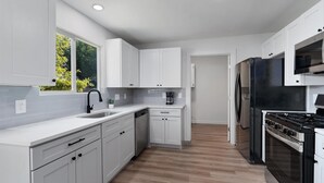 A modern kitchen with white cabinets, a stainless steel refrigerator, and a built-in oven.