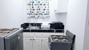 A compact kitchen with a gas stove, a sink, and a microwave. - SeaEsta Negril (Negril)