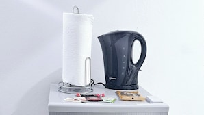 A two-door refrigerator with a paper towel holder and a kettle on top, placed against a white wall. - SeaEsta Negril (Negril)