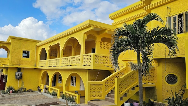 A yellow building with multiple balconies and a staircase. - SeaEsta Negril (Negril)