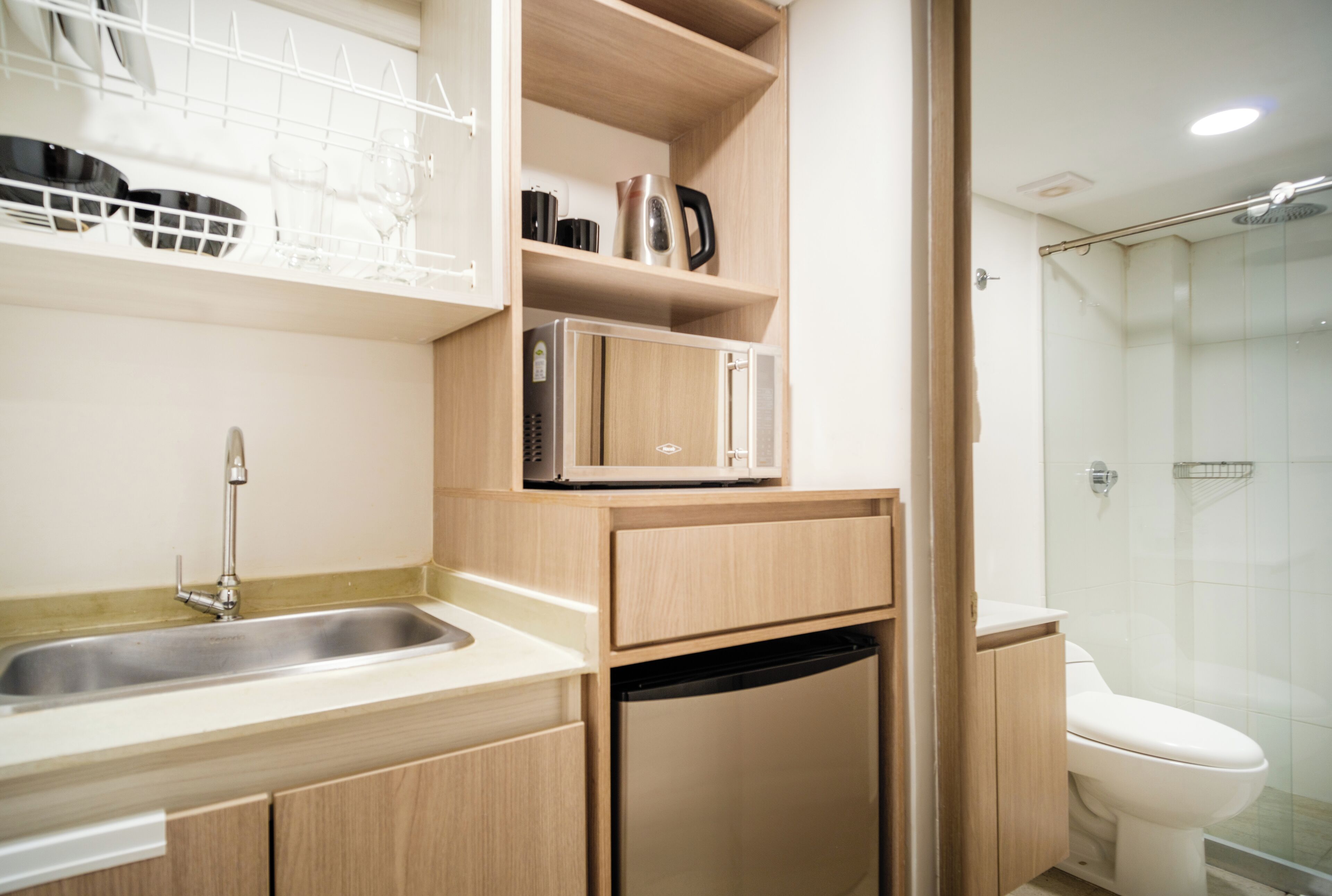 A compact bathroom with a sink, a microwave, and a toilet.