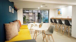 Un espace repas moderne avec un canapé jaune, une table ronde et des chaises noires.