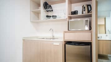 Una cocina compacta con lavamanos, microondas y lavavajillas integrado.
