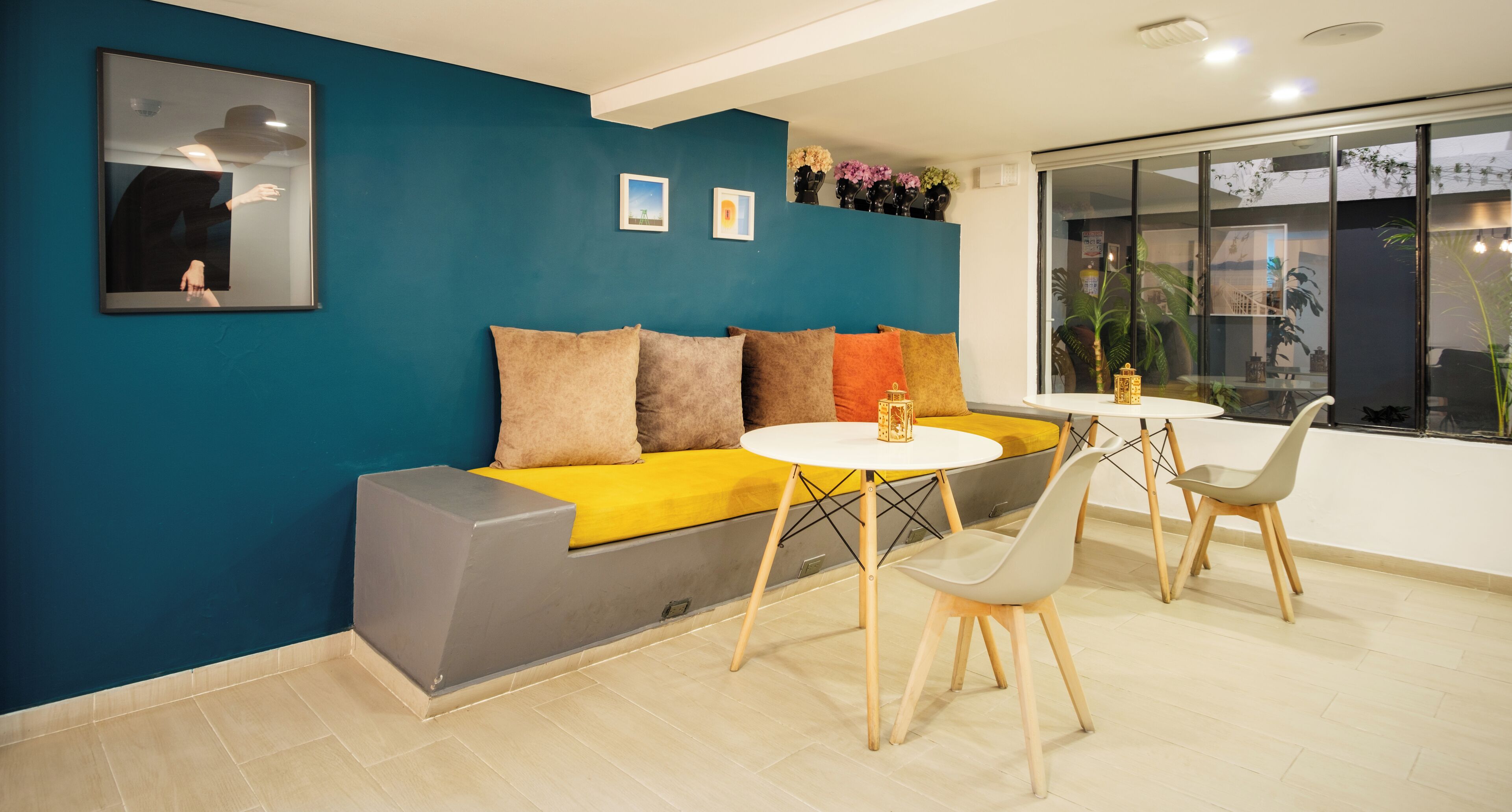 A modern living room with a blue accent wall, a sofa with multiple cushions, a round white table, and two chairs.