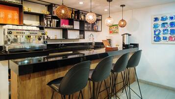 Uma cozinha moderna com máquina de café expresso integrada, banquetas e iluminação pendente.