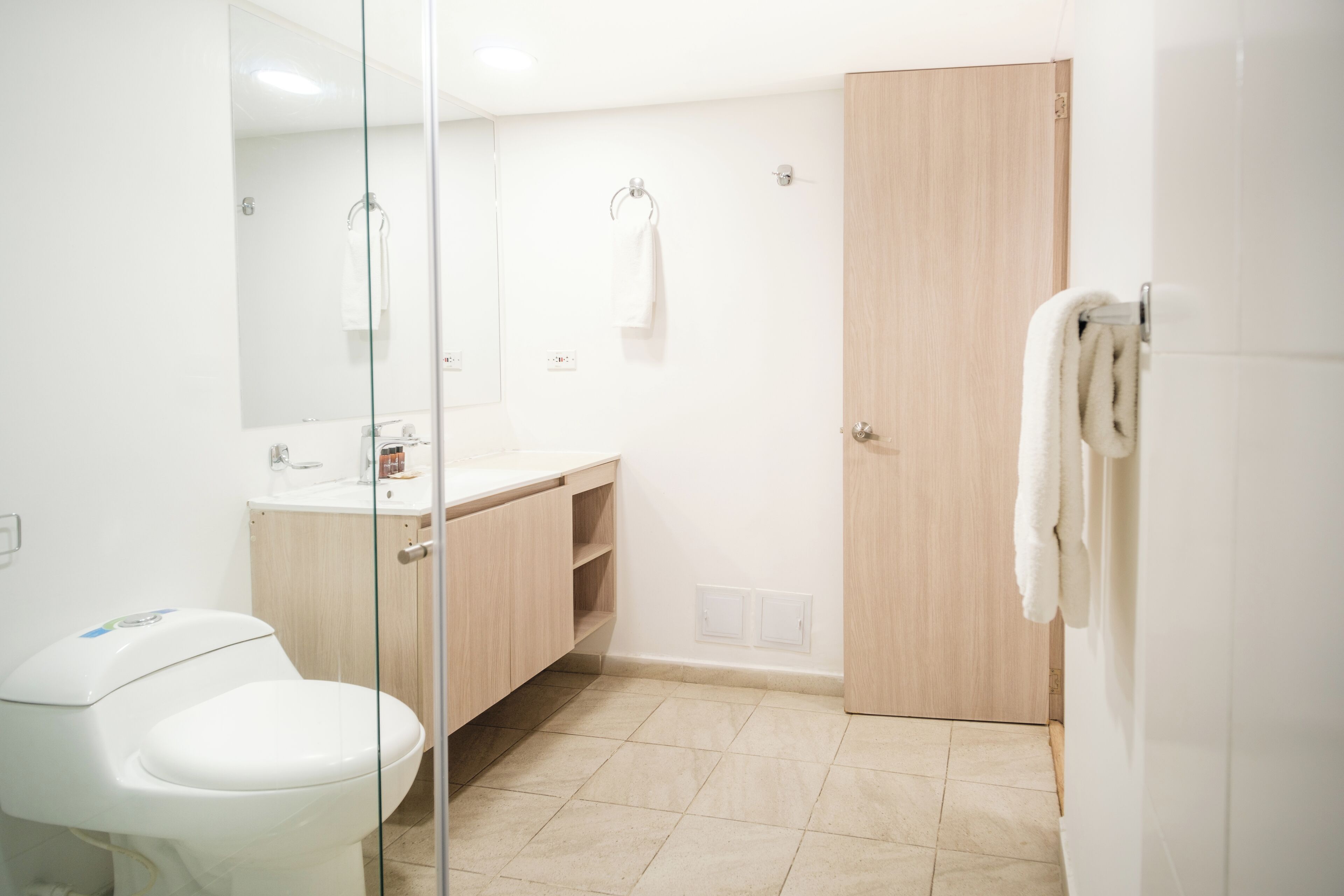 A modern bathroom with a toilet, sink, and mirror.