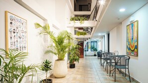 Un couloir agrémenté de plantes en pot, un escalier et un espace détente avec des chaises.