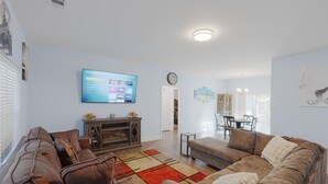 Ein Wohnzimmer mit großem Flachbildfernseher, zwei Sofas, einem Couchtisch und einem gemusterten Teppich.