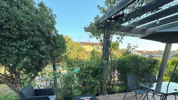 An outdoor patio with wicker furniture, a small table, and a pergola. - Family villa with pool, air-conditioning & independent studio. (Valergues)
