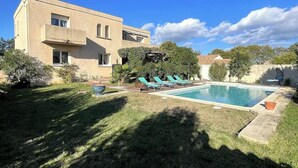 A two-story building with a swimming pool, surrounded by a well-maintained lawn and various plants. - Family villa with pool, air-conditioning & independent studio. (Valergues)