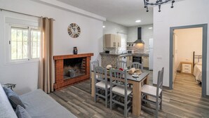 A modern living room with a fireplace, dining area, and kitchen. - PaperoDor Prado del Rey by Ruralidays (Cádiz)