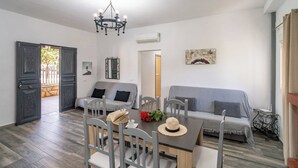 A dining area with a table, chairs, and a chandelier. There is a sofa and a small table with candles. - PaperoDor Prado del Rey by Ruralidays (Cádiz)