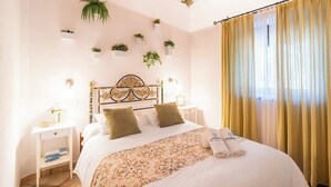 Una cama bien hecha con una colcha estampada, dos mesitas de noche con lámparas y un cabecero con un diseño decorativo.