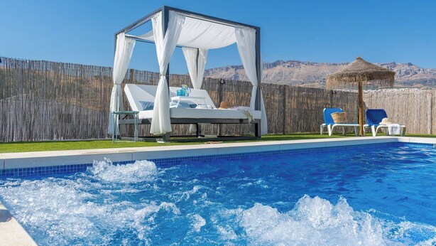 Una piscina con un jacuzzi y una estructura tipo sombrilla.
