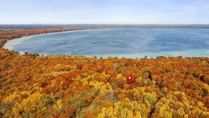 A coastal landscape with a forested area in autumn colors and a large body of water.