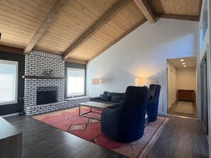 A modern living room with a fireplace, a sofa, and two armchairs.